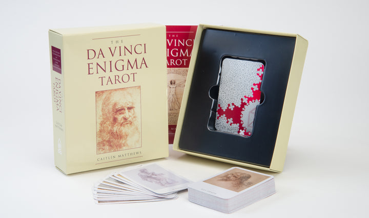 The Da Vinci Enigma Tarot (Deck and Guidebook Box Set) by Schiffer Publishing, Ltd. includes a deck in a tray, a tarot guidebook, and a box featuring Leonardo da Vinci’s sketch and red text.