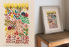 Split image: Left side displays a vibrant botanical embroidery on cream fabric. Right side features the same "Embroidery Garden" design by Schiffer Publishing, Ltd., framed and set on a wooden table against a plain white wall.