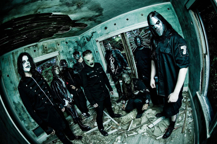 Nine people in black outfits and horror masks pose in a decaying, debris-strewn room—an image worthy of "The Art of Metal" by Schiffer Publishing, Ltd., evoking the chilling vibe of iconic heavy metal cover art.