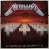 The Art of Metal by Schiffer Publishing, Ltd. showcases iconic heavy metal album artwork, like white cross-shaped graves at sunset with red hands above, and bold band logos framing the striking cover art.
