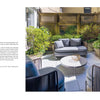 Repose in the Metropolis by Schiffer Publishing, Ltd. captures modern outdoor style with gray cushioned seating, a white table adorned with yellow flowers, and lush greenery along a wooden lattice fence—evoking NYC garden design charm.