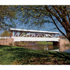 A white wooden covered bridge with a stone base crosses a calm creek amid greenery under a blue sky. Text reads, "Pennsylvania's Covered Bridges—Schiffer Publishing, Ltd." celebrating historic bridges of the region.