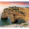 A panoramic view of Praia da Marinha, Portugal, with limestone cliffs and clear turquoise water at sunset, is featured in "The Wild Atlantic" by Schiffer Publishing, Ltd. The location description appears on the right.