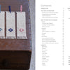 Five geometric woven bookmarks in red, blue, and purple—including hishizashi and Kogin styles—are arranged on a wooden chest beside the contents page of "Counted Sashiko Embroidery" by Schiffer Publishing, Ltd.