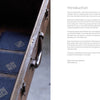 Six small square navy blue swatches with white counted sashiko embroidery from Schiffer Publishing, Ltd.’s Counted Sashiko Embroidery are arranged in an open vintage suitcase. A printed introduction and signature appear on the right.