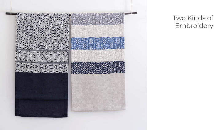 Two textiles hang side by side on a rod—one shows counted sashiko embroidery in black and white, the other displays Kogin designs in beige, blue, and white. Text on the right reads “Two Kinds of Embroidery.” Product: Counted Sashiko Embroidery by Schiffer Publishing, Ltd.