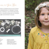 A young girl with short brown hair wears a handmade white floral crown from dried flowers and a yellow dress with blue embroidery. Next to her, Dried Flower Love by Schiffer Publishing, Ltd. displays dried flower craft materials outdoors on a table.