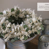 The "Dried Flower Love" from Schiffer Publishing, Ltd. displays a white and green dried flower wreath beside rustic candles—perfect for charming décor when guests arrive.