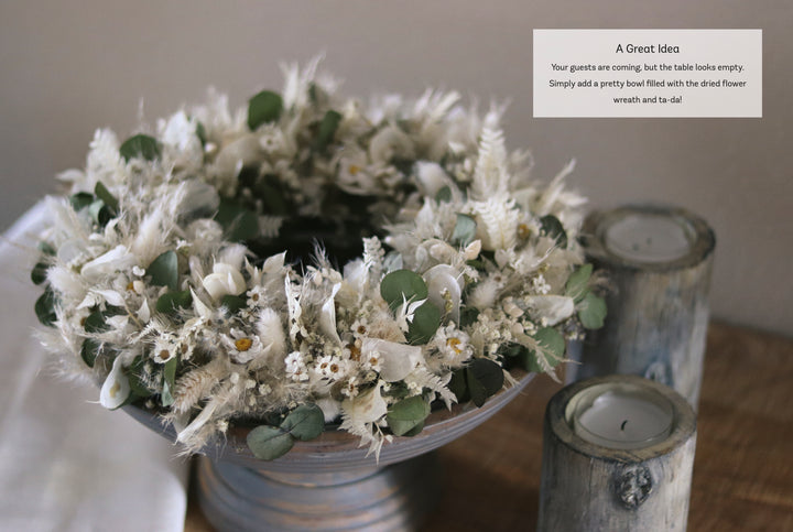 The "Dried Flower Love" from Schiffer Publishing, Ltd. displays a white and green dried flower wreath beside rustic candles—perfect for charming décor when guests arrive.