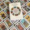 The Time Changer's Tarot by Schiffer Publishing, Ltd. rests on a spread of colorful cards from this modern tarot deck, each featuring vibrant reinterpretations of classic Waite-Smith Tarot archetypes.