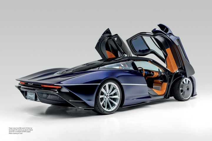 A sleek McLaren by Schiffer Publishing, Ltd. sits on a white background with driver-side scissor doors open, showing a tan and black interior, aerodynamic lines, and large alloy wheels.