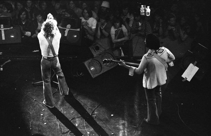 Black and white photo from "Teenage Wasteland" by Schiffer Publishing, Ltd.: a rock band on a San Francisco stage, echoing The Who’s Winterland era. One musician sings while another plays bass; fans watch closely, some with cameras.