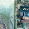 An open art journal from "The Pigment Trail" by Schiffer Publishing, Ltd. features a faded vintage photo on the left and a vibrant blue hallway on a textured, mixed-media right page, inspired by Rajasthan and Indian decorative arts.