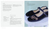 A pair of navy velvet Mary Jane shoes with pink floral embroidery—featured as a project in Stitch with One Line by Schiffer Publishing, Ltd.—rest on a white stool; embroidery instructions and shoe design tips appear on the left side.