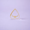 The Crystal Spirit Talking Board and Guidebook by Schiffer Publishing, Ltd. is a transparent, heart-shaped board with a circular top hole and gold design, standing upright on a light purple surface, radiating sacred crystal energy.