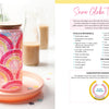 A glass tumbler with a wooden lid and straw, decorated in colorful rainbows, sits on a peach plate with floral accents. Next to it is "Sublimation Crafting" by Schiffer Publishing, Ltd., featuring a Snow Globe Tumbler guide.