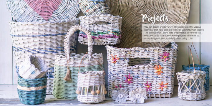A display of Weaving Paper baskets by Schiffer Publishing, Ltd.—upcycled waste paper baskets in assorted shapes and sizes, some with colorful accents and flowers, arranged on light wood with a large patterned basket in the background.