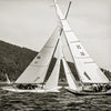 Two sailboats with large white sails race side by side on a lake, leaning together in the wind. "The Maine Coast" by Schiffer Publishing, Ltd. captures this scene against a backdrop of forested hillsides, echoing Michael Kahn’s classic style.