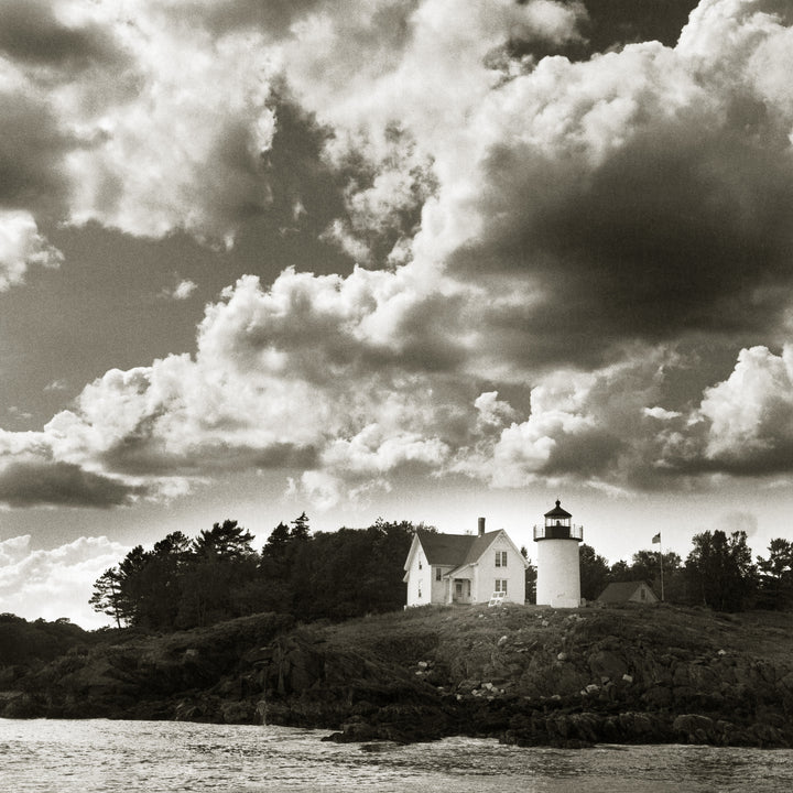 The Maine Coast" by Schiffer Publishing, Ltd. showcases a white lighthouse and house on a rocky shore under a dramatic sky—black-and-white seascape photography capturing Maine's timeless beauty.
