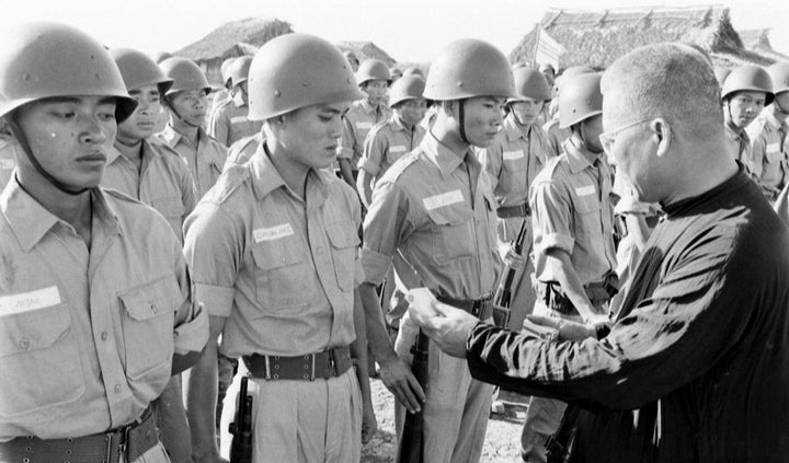 A man in dark clothing inspects young soldiers standing at attention outdoors with tents behind them—a scene from The Fighting Fathers by Schiffer Publishing, Ltd.