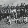 A black-and-white photo from "The Fighting Fathers" (Schiffer Publishing, Ltd.) shows soldiers—some linked to CIA South Vietnam ops—posing outdoors with rifles or submachine guns in mixed uniforms and hats, standing, kneeling, or prone on the grass.