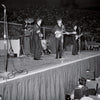 A black and white photo in Schiffer Publishing, Ltd.'s "The Beatles in America" captures the band's energetic stadium performance, with amplifiers, guitars, and cheering floor-to-stand crowds visible.