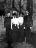 Four people pose outside a brick building: two men in military-style uniforms and two women in skirts and blouses. The black and white image evokes US Navy history, echoing the spirit of "King's Navy" by Schiffer Publishing, Ltd.