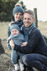 A man hugs two children outdoors, all in matching blue outfits inspired by "Winter Knitting for Little Sweethearts" from Schiffer Publishing, Ltd., perfect for a chilly day that highlights cozy Nordic design and style.