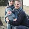 A man hugs two children outdoors, all in matching blue outfits inspired by "Winter Knitting for Little Sweethearts" from Schiffer Publishing, Ltd., perfect for a chilly day that highlights cozy Nordic design and style.