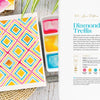 The "Modern Watercolor Workshop" by Schiffer Publishing, Ltd. features a vibrant diamond trellis watercolor painting alongside a spiral sketchbook, paintbrush, and four bright paints—pink, yellow, blue, and orange—ideal for beginner projects.
