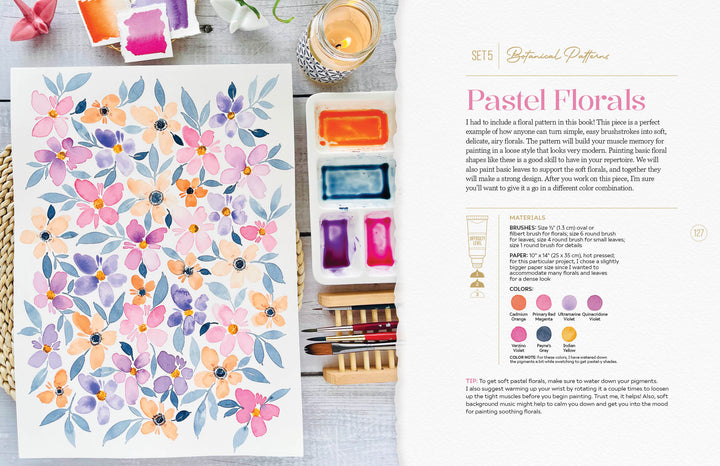 The Modern Watercolor Workshop by Schiffer Publishing, Ltd. features a vibrant watercolor painting with pink, orange, and purple flowers on a table with palettes, brushes, a candle, and water—ideal for beginner creative projects.