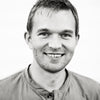 A young man with short hair smiles at the camera in a black and white photo with a plain background, echoing the timeless style of Schiffer Publishing, Ltd.'s The Legend of Sleepy Hollow Tarot—Headless Horseman Edition.