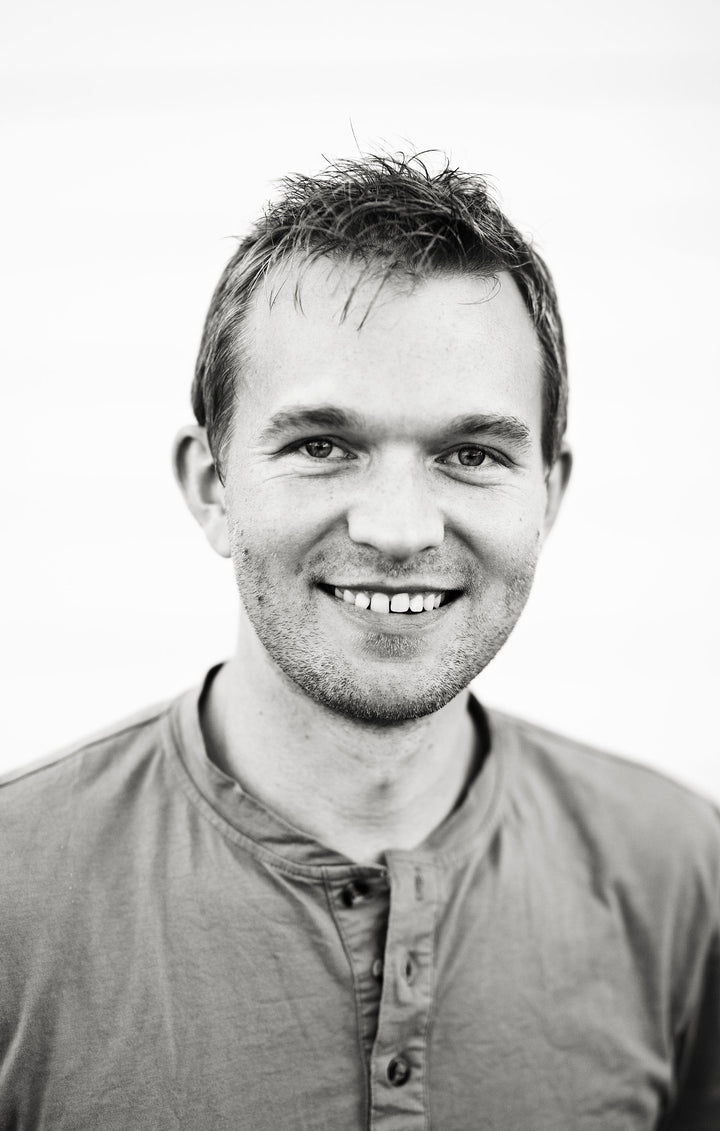 A young man with short hair smiles at the camera in a black and white photo with a plain background, echoing the timeless style of Schiffer Publishing, Ltd.'s The Legend of Sleepy Hollow Tarot—Headless Horseman Edition.