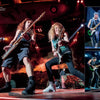 Two long-haired guitarists rock out under colorful stage lights, with three side photos of a blue-haired guitarist evoking Iron Maiden. Relive these classic heavy metal moments in Hallowed By Their Name: The Unofficial Iron Maiden Bible by Schiffer Publishing, Ltd.