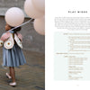 A girl wears a Magical Crochet creation from Schiffer Publishing, Ltd., featuring whimsical balloon motifs and inventive crochet patterns—perfect for inspiring creativity in children.