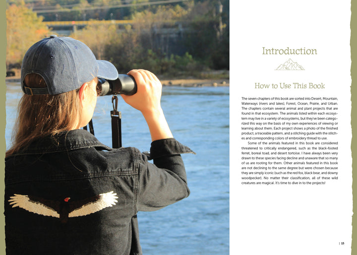A person in a black jacket with white bird wing embroidery inspired by North American wildlife scans a riverside with binoculars. On the right, text introduces "The Field Guide to Embroidery" by Schiffer Publishing, Ltd.