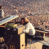 A musician reminiscent of Richard Manuel performs on keyboards at an outdoor stadium concert before a large crowd, capturing classic rock vibes. Sound equipment and cables are visible in the foreground. Brand: Schiffer Publishing, Ltd.