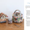 Three quilted miniatures—a house, a handled basket, and a pincushion—rest on a wooden table with scissors and thread. Find instructions for these charming projects in Kawaii Appliqué Quilts from Japan by Schiffer Publishing, Ltd.