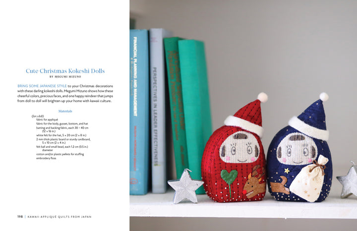 The book "Kawaii Appliqué Quilts from Japan" by Schiffer Publishing, Ltd. rests on a white shelf with books, plants, and silver stars, creating a festive and cozy holiday display inspired by Japanese quilting.