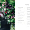 A row of glass jars with pink, purple, and white flowers sits on a dark outdoor table; next to them is "Starting Your Floral Design Studio" by Schiffer Publishing, Ltd., opened to the contents page on floral techniques and eco-friendly arranging.