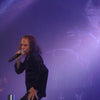 A male rock singer with long hair passionately performs on stage, echoing Ronnie James Dio as he belts out "Holy Diver," purple lights and fog evoking the Dio band vibe—just like the spirit captured in Schiffer Publishing, Ltd.'s DIO: The Unholy Scriptures.