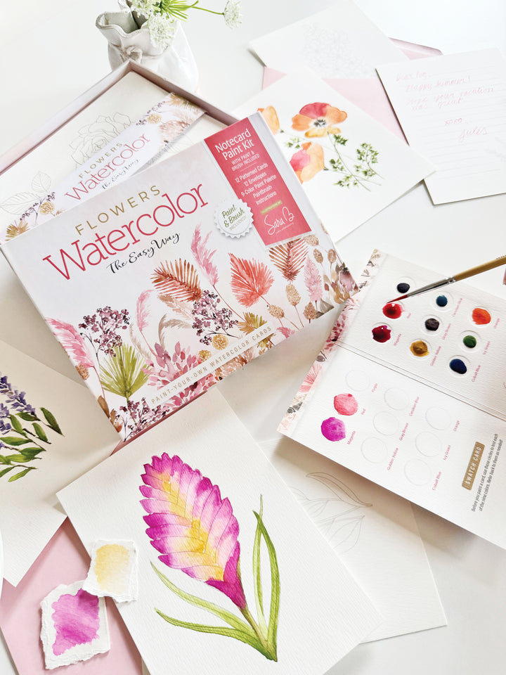 The Watercolor the Easy Way Paint-Your-Own Watercolor Cards Flowers kit by Schiffer Publishing, Ltd. is displayed with paints, a brush, flower illustrations, finished floral artworks, and charming watercolor notecards on a white surface.
