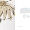 The book "Projects and Techniques for Metal Clay Jewelry" by Schiffer Publishing, Ltd. is shown on a beige palm leaf alongside instructions and materials, its cover featuring an elegant metal choker with a spiral shell pendant.