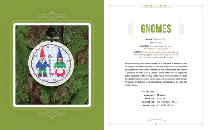 An embroidery hoop with two stitched gnomes—one blue, one green—hangs on a tree trunk beside a text page from "Monsters and Mayhem in Cross-Stitch" by Schiffer Publishing, Ltd., detailing gnome lore and cross-stitch patterns.