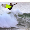 A surfer in a wetsuit launches above the wave, yellow and white board airborne—embodying the thrill of discovering uncharted breaks, as seen in surfEXPLORE by Schiffer Publishing, Ltd., with ocean spray all around.