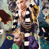 A surreal collage from Schiffer Publishing, Ltd.’s Couture Tarot depicts the Queen of Cups in a jeweled headdress, striped fur scarf, and bold earrings, surrounded by fashion tarot motifs like a black purse, gemstones, and peacock feathers.