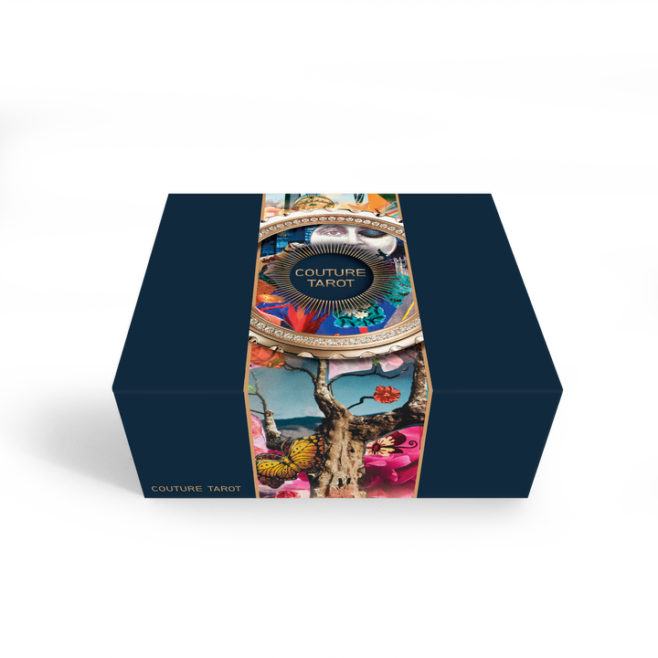 Couture Tarot by Schiffer Publishing, Ltd. comes in a dark blue box with a vibrant artistic band adorned with butterflies, birds, and a tree, reflecting the unique fashion-inspired tarot cards inside.