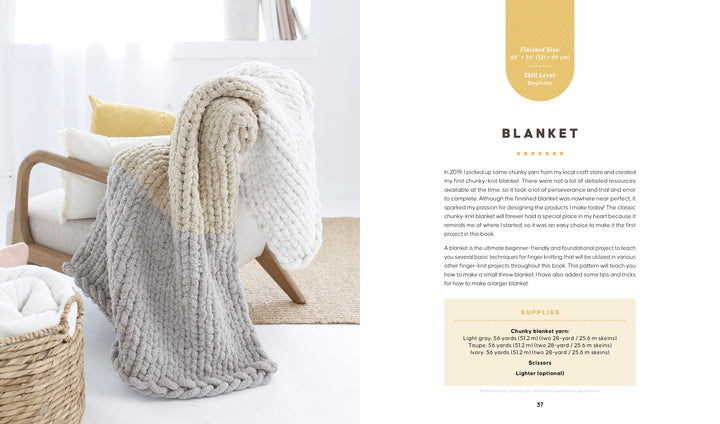 A cozy beige and gray chunky knit blanket is draped on a modern chair with yellow and white pillows. Beside it is "Get Started in Finger Knitting" by Schiffer Publishing, Ltd., showing a pattern page and blanket-making supplies.