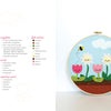 The Felt Craft Fun kit by Schiffer Publishing, Ltd. features a vibrant embroidery hoop with smiling pink, white, and yellow flowers, green leaves, bees, and clouds on a blue sky—ideal for beginners with instructions and materials list included.