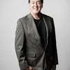 A man with short dark hair in a gray blazer, black shirt, and blue jeans smiles with one hand in his pocket against a plain background, echoing the style found in "Robert C. Jackson" by Schiffer Publishing, Ltd.